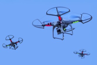 Three miniature quadcopter drones, teleoperated unmanned aerial vehicles, UAV equipped with cameras