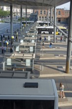 Commuters waiting for transit buses at bus stop of public transport company De Lijn at train