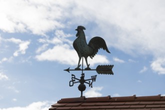 Metal weather vane against a clear sky and scattered clouds, Baden-Württemberg, Germany