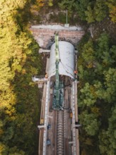 Drone photo of a crane working on a tunnel structure in an autumn environment, built by Hermann,