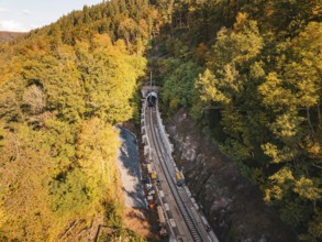 Layered view of an autumn rail construction site in the forest with construction vehicles,