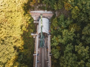 Aerial view of a tunnel boring machine working in a wooded area on a railroad track, built by