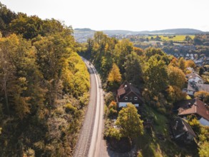 Village in autumn landscape next to railroad tracks and view of hills, building of Hermann, Hesse,