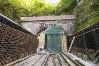 Entrance area of a tunnel during construction with scaffolding in the forest, construction of