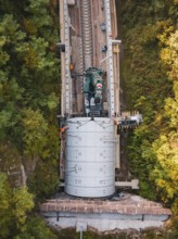 Machine building tracks in an autumnal forest area placed on a railroad track, construction of