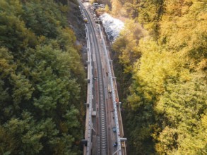 Construction work on tracks in autumn forest, under bright sunshine, construction of Hermann,