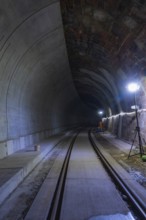 Tunnel with rails and bright lighting along the wall, dark building atmosphere, Hermann building,