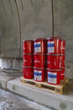 Red paint buckets on a pallet in a tunnel setting, building materials stored, building of Hermann,