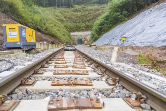 Rails lead to a tunnel surrounded by gravel and construction machinery, built by Hermann, Hesse,