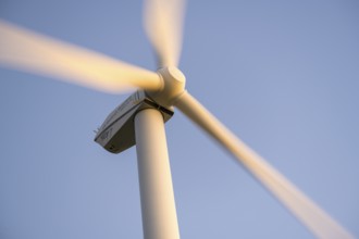 Wind turbine with rotating blades moving against a clear sky, Baden-Württemberg, Germany