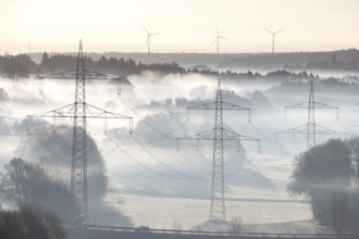 Foggy landscape with power poles and wind turbines at dawn, Swabian Jura, Baden-Württemberg,