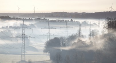 Foggy landscape with power poles and wind turbines in dawn light, Swabian Alb, Baden-Württemberg,