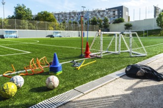 Artificial grass soccer field with multiple training equipment including cones, hurdles, a small