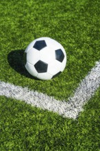 Soccer ball sits on the corner kick line of green artificial turf, ready for play symbolizing