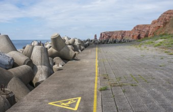 Coastline with concrete tetrapods by the sea, coastal protection, protective wall, paved coastal