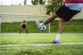 Soccer player preparing to kick a penalty shot towards the goal, with a vigilant goalkeeper in
