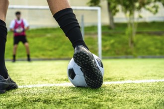 Soccer players foot about to strike the ball for a penalty, blurred goalkeeper in background on