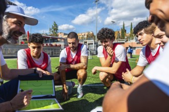 Soccer coach outlining a game strategy on a clipboard with a marker while adult and young male