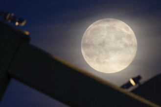 The full moon sweeps along the Frankfurt evening sky and passes the pillars of the rafter bridge,