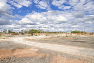 View in a limestone quarry with heavy machinery by a gravel road on a sunny summer day
