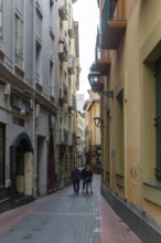 People walking along narrow alleyway street in the Old Town area, city ofZaragoza, Aragon, Spain