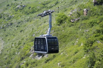 A cable car floats over green hilly terrain in a mountainous landscape, Tatev cable car, Wings of