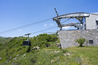 Cable car station with gondola in a green landscape, stone wall and bright blue sky, Tatev cable