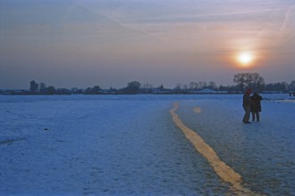 People walk across ice rink, sunset, frozen Elbe, Bleckede, Lower Saxony, Germany, February 9,