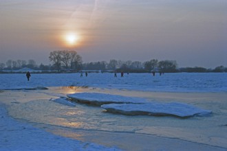 People walk across ice rink, sunset, frozen Elbe, ice floes, Bleckede, Lower Saxony, Germany,