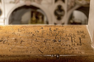 Initials, inscriptions, signs, doodles, graffiti, carved by bored churchgoers in church stalls,