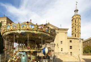 Funfair merry-go-round next to Church of San Juan de los Panetes with its Mudéjar tower, Zaragoza,