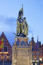 Illuminated monument to Jan Breydel and Pieter de Coninck in the evening light on the market square