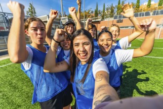 Happy young women's soccer team members celebrate a sports victory together on the green turf,
