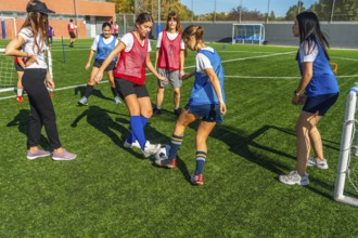 Young women soccer players are practicing passing and dribbling drills on a green artificial turf