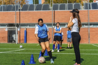 Female soccer players receiving instructions from their coach during a practice session on a green