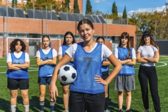Confident young adult women soccer players standing together on the artificial grass football