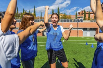 Excited female soccer players celebrating success and victory together, raising their arms in