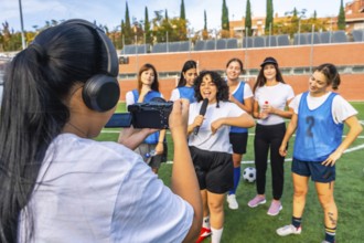 Woman videographer in headphones filming a dynamic interview with a joyful woman holding a