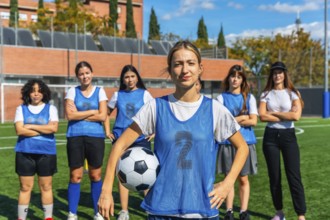 Diverse group of confident young women forming a soccer team, standing together on a green football