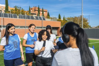 Diverse group of women soccer players being interviewed by a journalist with a microphone and