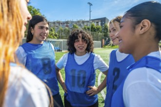 Diverse young women soccer team huddling on a green sports field, collaborating and discussing