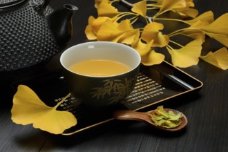 Ginkgo tea in tea bowl and ginkgo leaf, tea leaves in a spoon, ginkgo biloba