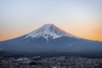 View of Mount Fuji volcano over Fujiyoshida City, at sunset, Yamanashi Prefecture, Japan