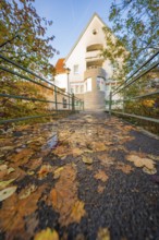 Autumn bridge with fallen leaves leading to a house, Aidlingen, Böblingen district, Germany