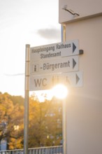 Signpost with sunbeams surrounded by autumn trees under a clear sky, Aidlingen, Böblingen district,