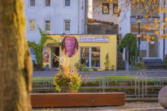 Yellow pizza building on a sunny street surrounded by autumn plants, Aidlingen, Böblingen district,