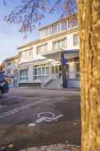 Modern building complex with parking lot and wheelchair-friendly markings, autumnal atmosphere,