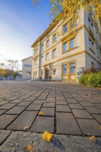 Two-story building with autumn leaves on the forecourt, under blue sky, Aidlingen, Böblingen