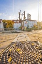 Urban scene in autumn with cobblestones, church in the background and sunny sky, Aidlingen,
