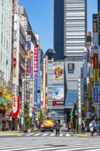 Bustling street scene in Japan with modern buildings and colorful billboards, figure of Godzilla